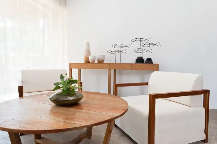 Minimalist living room with maple wood coffee table, cushioned chairs, console table, and decor pieces
