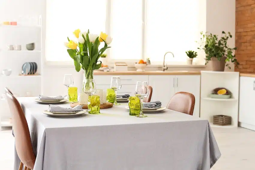 Modern dining room features a table set up with polycotton blend tablecloth and vase of tulip flowers