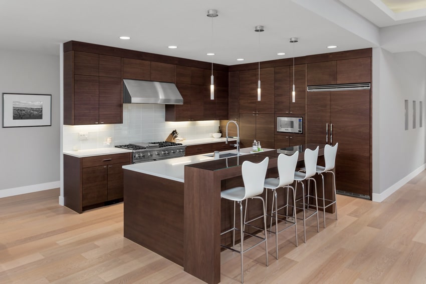 Modern kitchen with bar counter, high chairs, laminate cabinets, stove, range hood, countertop, and wood floors