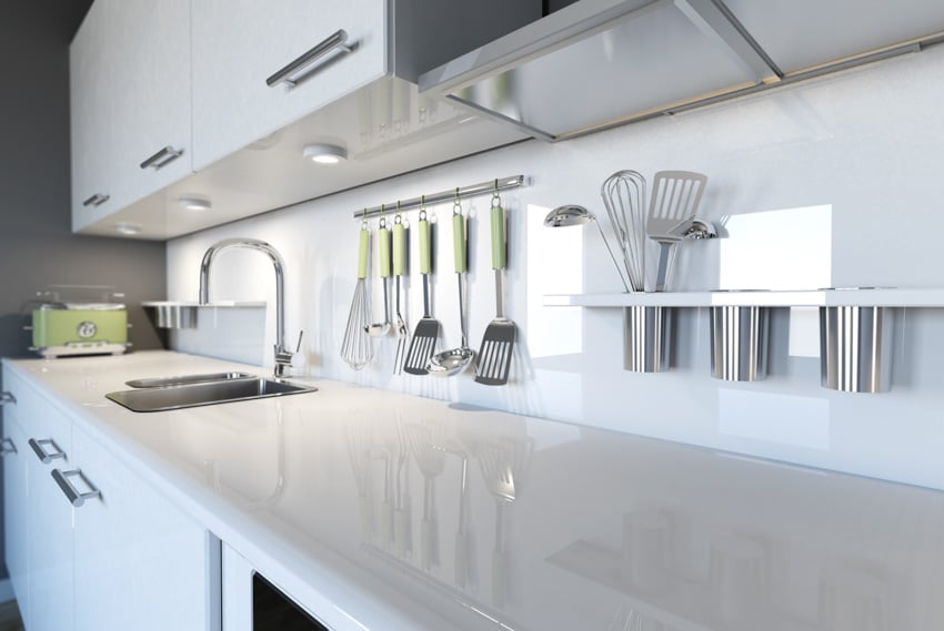 Modern kitchen with white laminate countertops, white cabinets, laminate backsplash, sink, and faucet