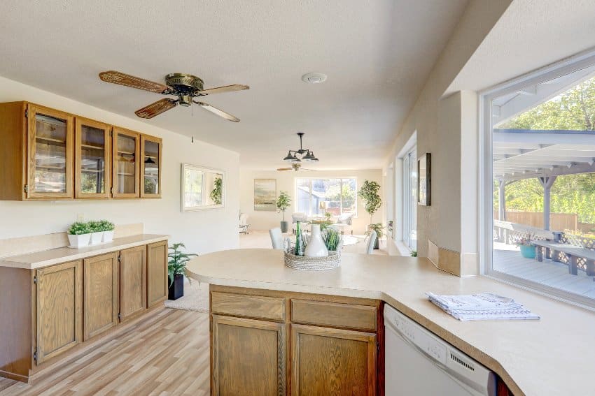 Open floor plan showing kitchen with wood cabinets with glass fronts and ceiling fan