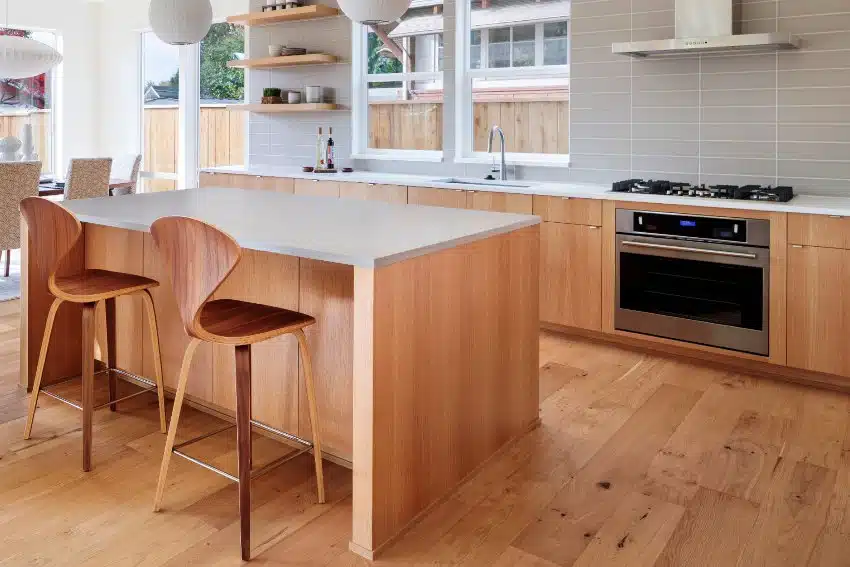 Kitchen with alderwood flooring, bar stools, vertical tile backsplash and windows
