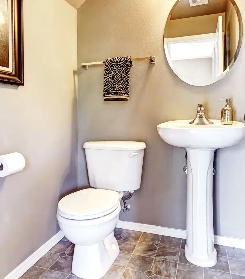 Small bathroom interior with tile floor, pedestal sink and small mirror