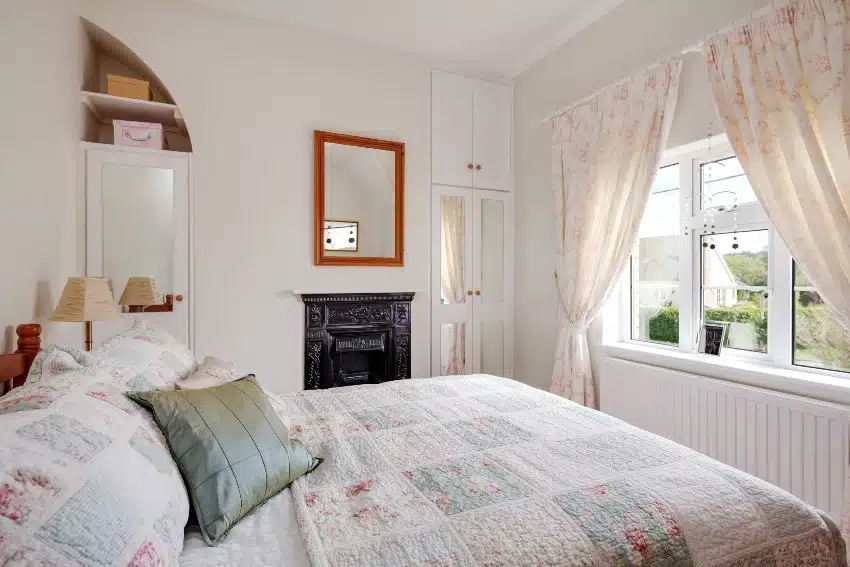 Bedroom with antique cast iron fireplace, built in cupboards and mirror 
