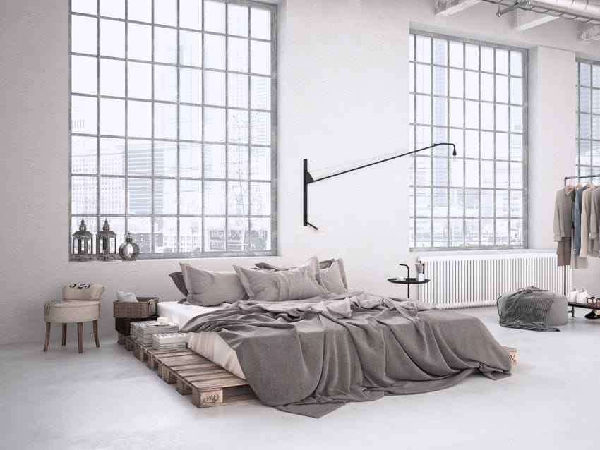 Farmhouse industrial bedroom with windows, bed, pillows, comforter, and ottoman pouf