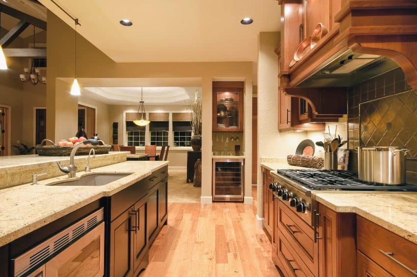 Traditional kitchen features wooden cabinets wih legs, granite countertops and hardwood floors