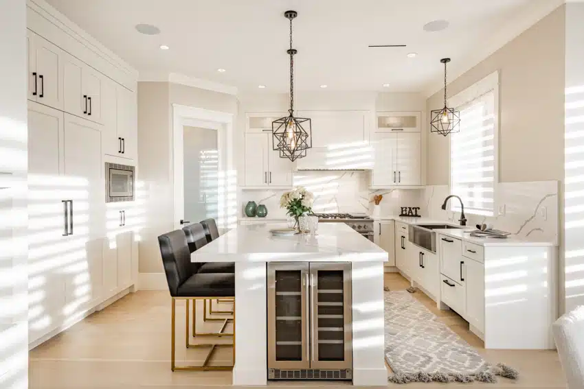 Transitional kitchen with island, high chairs, white cabinets, pendant lights, wine cooler, countertop, backsplash, and windows