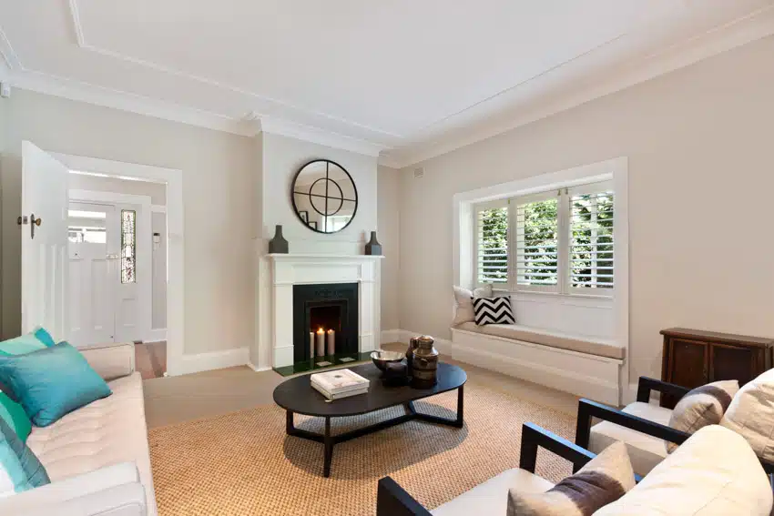 Transitional living room with fireplace, coffee table, wall sconces, windows, chairs, and sofa