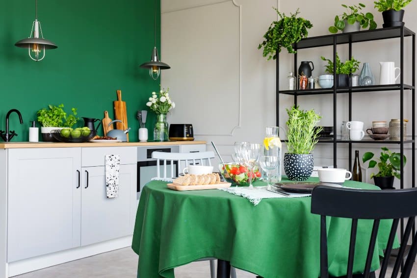 Trendy kitchen with dining table with green polyester tablecloth set for romantic dinner