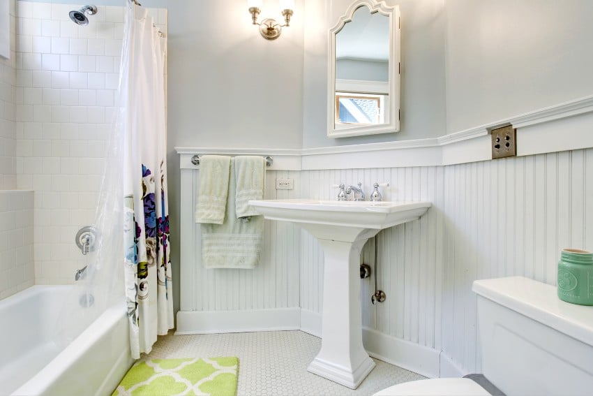 Vintage style bathroom with white interior, pedestal sink and decorative shower curtain