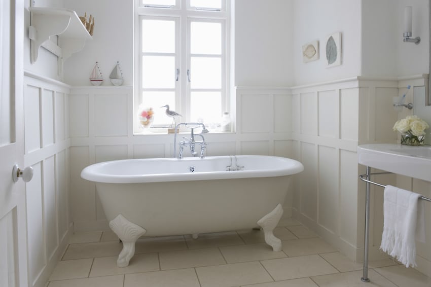 White bathroom with casement window, clawfoot tub, tile floor, and towel holder