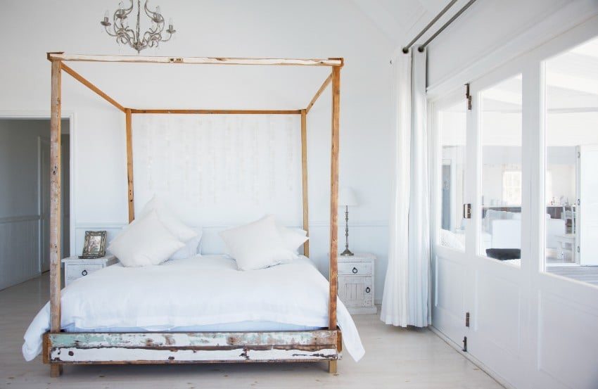 White bedroom with antique bed frame and chandelier