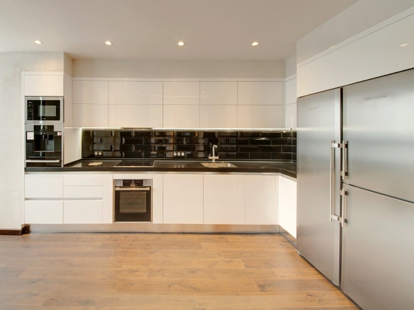 White fitted kitchen with a black backsplash and a wooden floor