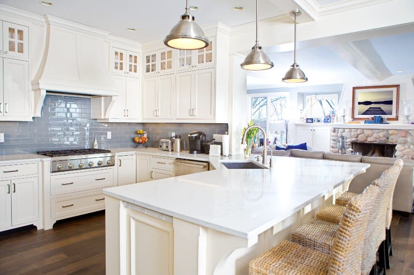 White kitchen cabinets with wood legs, hardwood floors, island with chairs