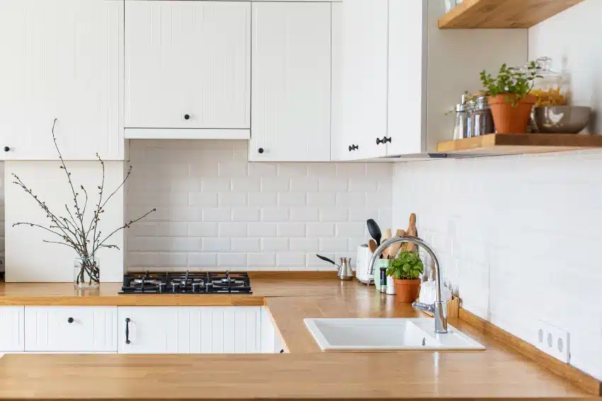 Kitchen with woodlike counter, white cabinets and white subway backsplash