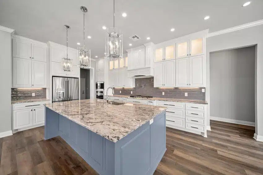 Craftsman kitchen with granite countertop, island, white cabinets, tile backsplash, wood flooring, and pendant lights