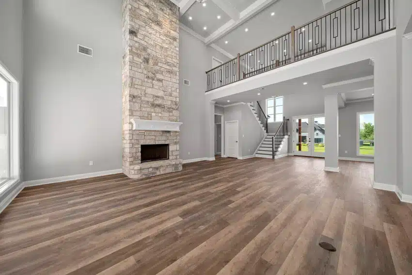 Craftsman living room with wood flooring, stone fireplace, second floor, staircase, windows, and door
