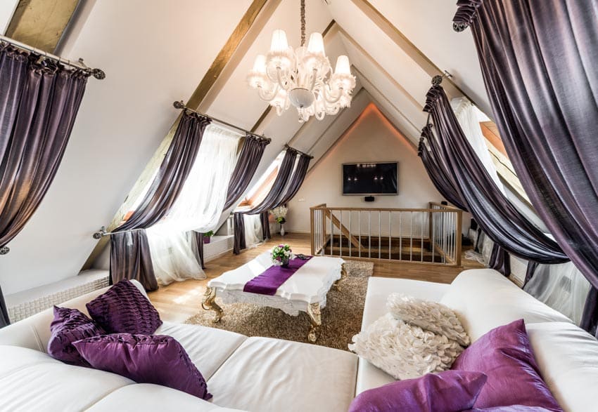 Attic living room with chandelier, window, curtains, sofa, coffee table, and floor rug