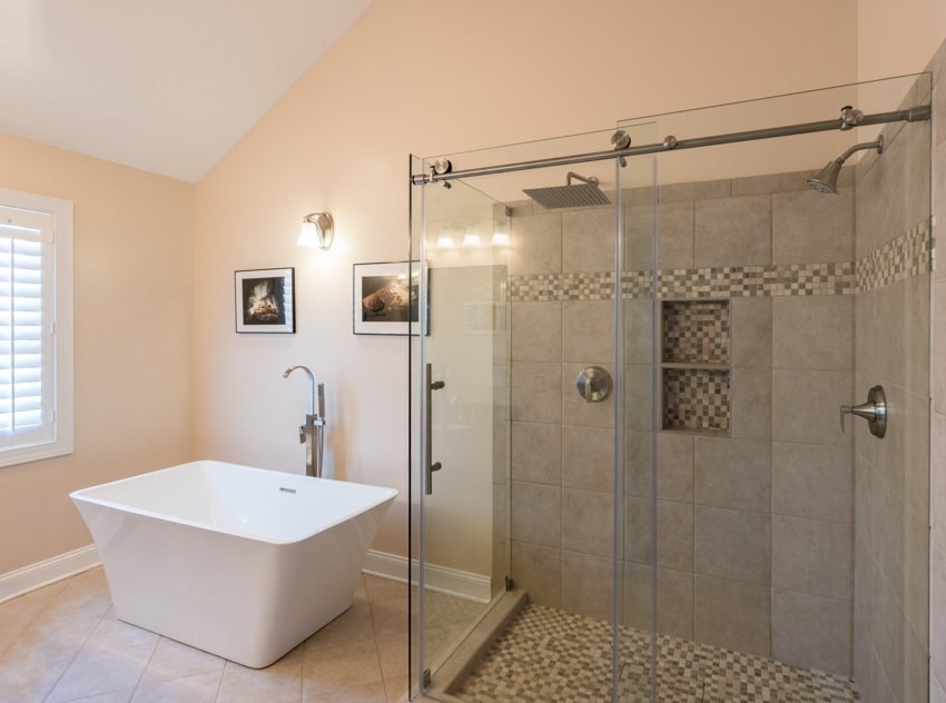 Bathroom with bypass shower doors, tub, faucet, wall sconce, shower, pebble flooring, and window