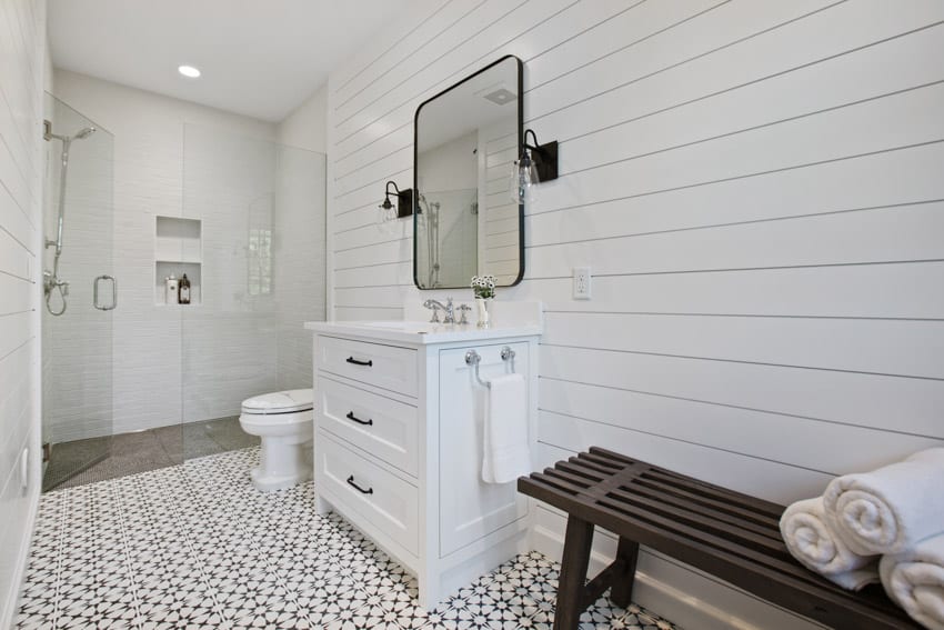 Bathroom with farmhouse shiplap, patterned tile, and black wall sconces