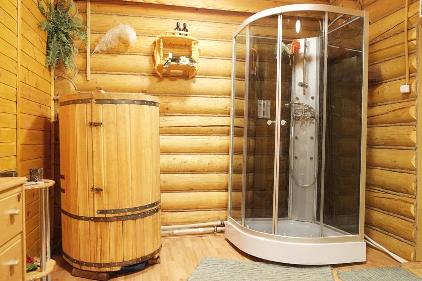 Bathroom with shower sauna combo, log walls, and cedar wooden bucket