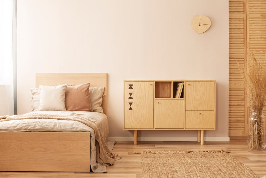 Bedroom with modern dresser, footboard, comforter, pillows, room divider, and wall clock