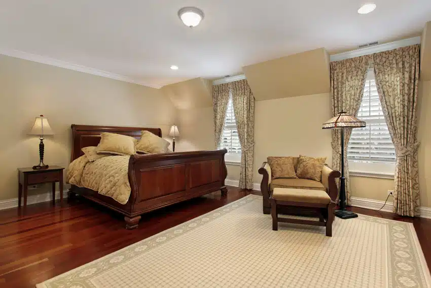 Bedroom with accent chair, carpet, headboard, footboard, comforter, and pillows