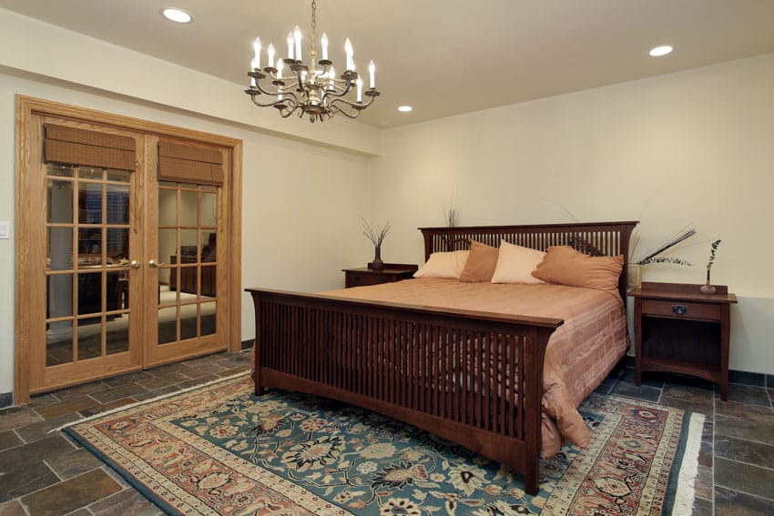Bedroom with mission style oak furniture, footboard, nightstands, carpet, tile floor, chandelier, and glass door