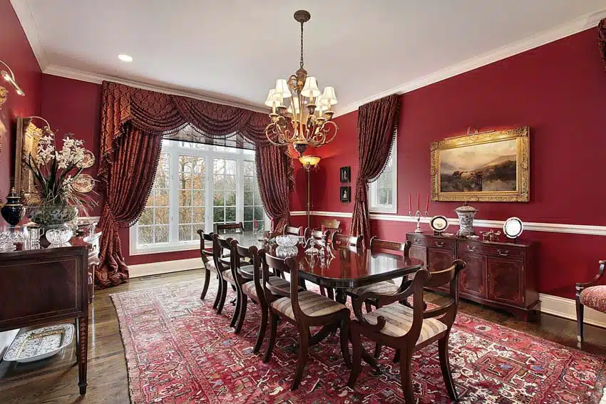 Classic room with red walls, floor carpet, curtains, and chandelier