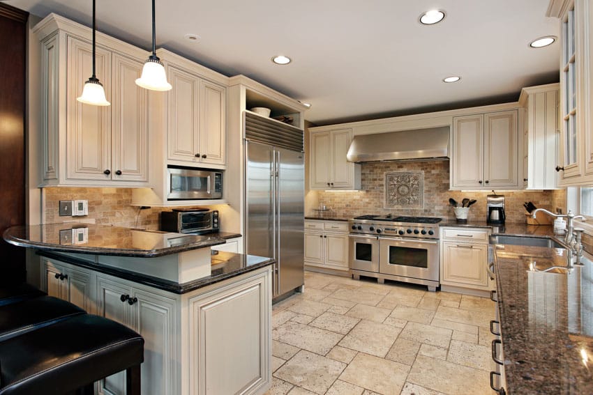 Classic kitchen with tile floors, wood cabinets, tile backsplash, countertop, and pendant lights