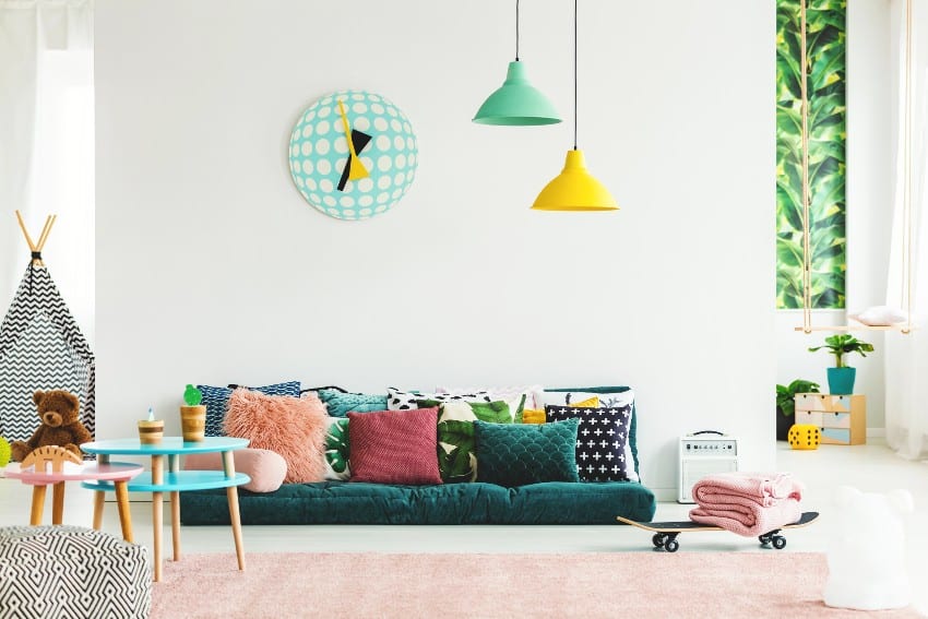 Playroom with skateboard, big clock on the wall and multi functional furniture including green sofa and pillows