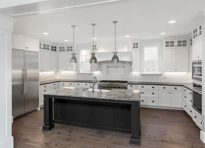 Contemporary kitchen with dolomite countertop, island, white cabinets, backsplash, refrigerator, pendant lights, and wooden floors