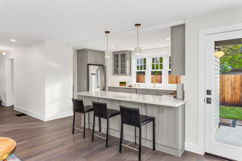 Contemporary kitchen with peninsula, high chairs, pendant lights, and glass cabinets