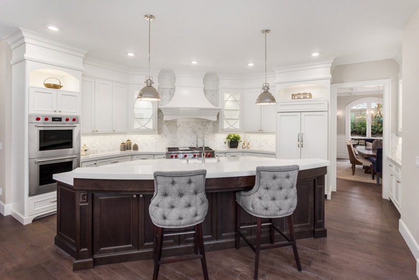 Contemporary kitchen with white solid surface corian countertops, raised breakfast bar, island, and white cabinets