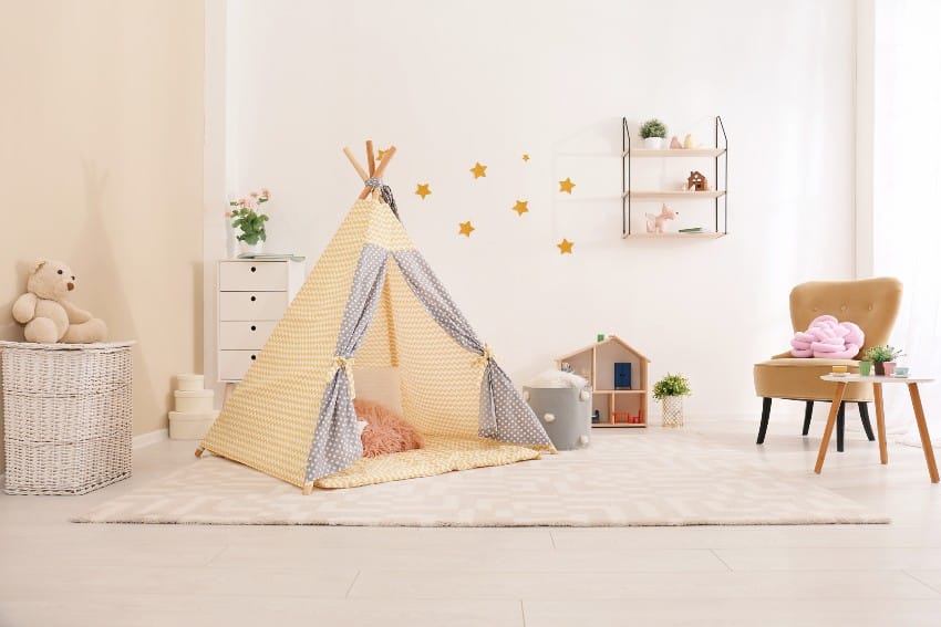 Cozy kids game playroom interior with play tent, rug, chairs, dresser, and toys