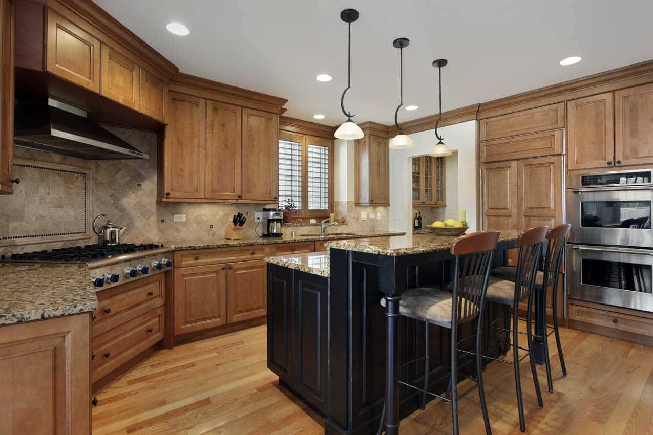 Craftsman kitchen with island, high chairs, wood floors, cabinets, backsplash, and Santa Cecilia granite countertop