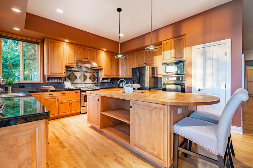 Craftsman kitchen with pendant lights, island, wooden floors, chairs, backsplash, cabinets, and windows