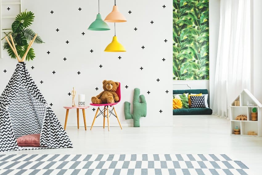 Creative minimalist playroom interior decorated with colorful lamps, cactus pillow and banana leaves on the wall