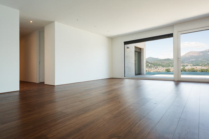 Empty room with white walls, finished wood floors, and glass door