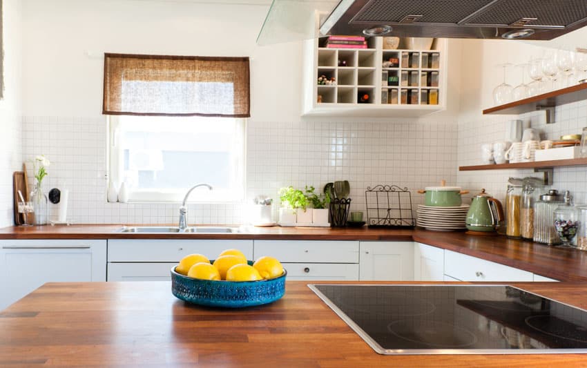 Farmhouse kitchen with stove, tile backsplash, and teak wood countertop