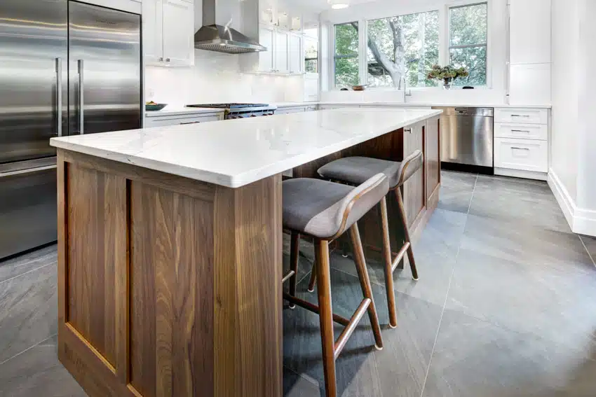 Farmhouse kitchen with, island, countertop, bar stools, refrigerator, windows, slate tile floors, and cabinets
