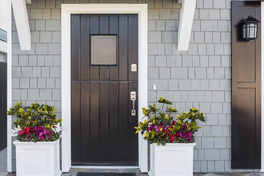 Gray house exterior with black front door, shingle wall cladding, and flowers