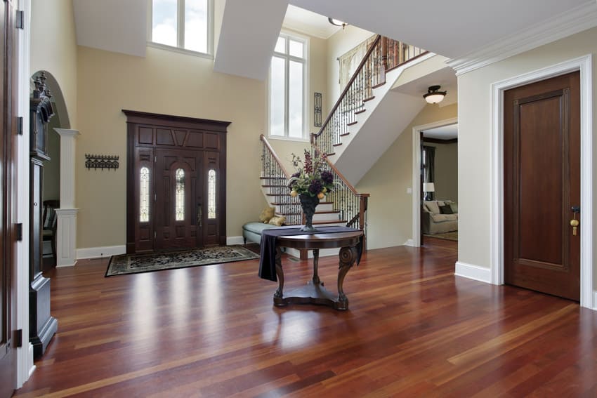 House entranceway with round table, staircase, wood door, and finished wood floors