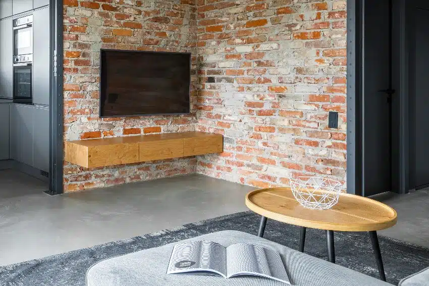 Industrial style farmhouse living room with round coffee table, TV, and brick wall