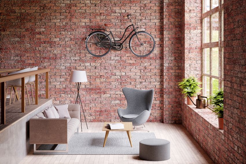 Industrial farmhouse style living room with big window, gray couch and chair, and bicycle on the red brick wall