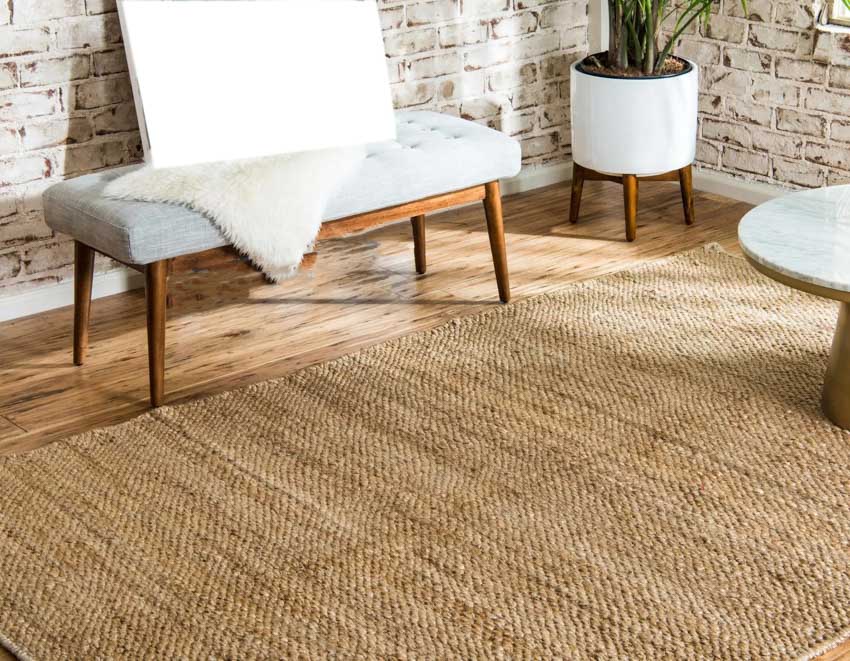 Jute rug for living rooms with cushioned bench, brick wall, and indoor plant