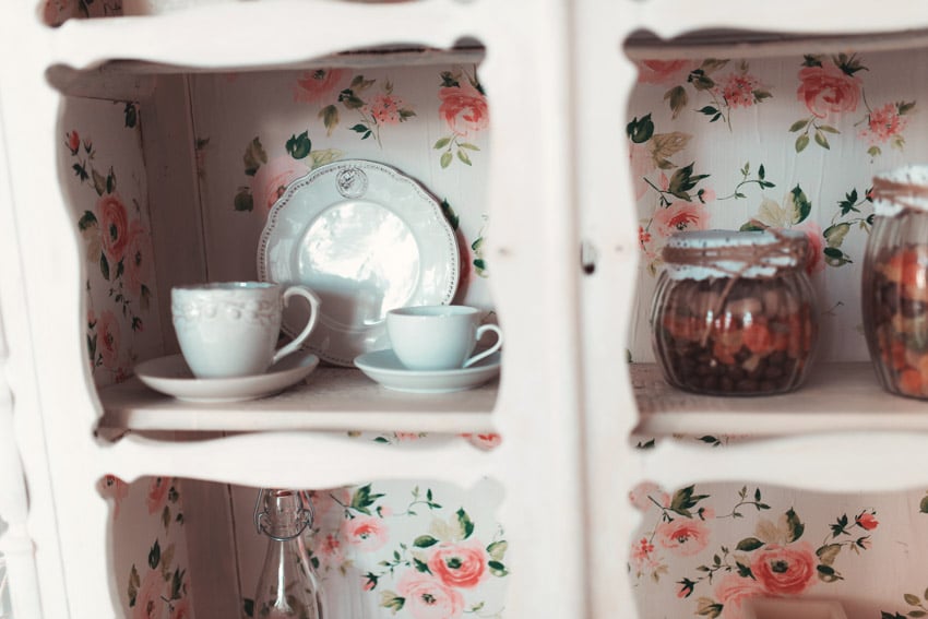 Kitchen with wallpaper inside cabinet with cups, jars, and plates