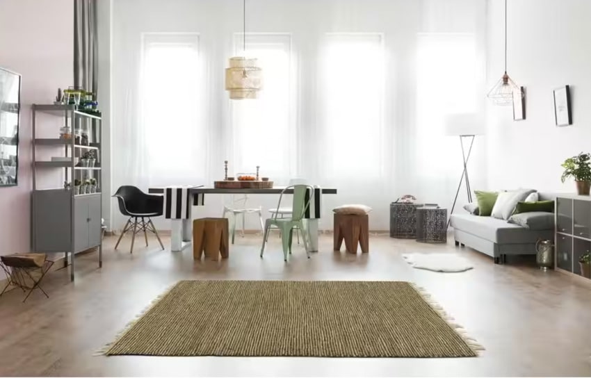 Living room and dining room combo with hemp rug, wood floor, couch, freestanding shelves, pendant lights, and windows