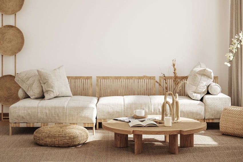 Living room with decorative coffee table, sofa, pouf, carpet, pillows, and white wall