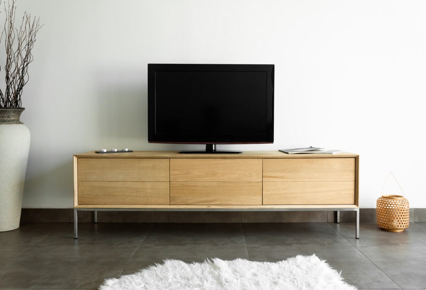 Room with oak wood television stand, epoxy flooring floor, vase, and white rug